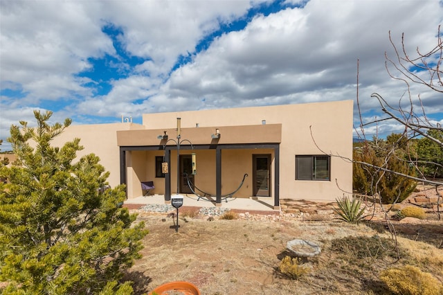 rear view of property with stucco siding and a patio area