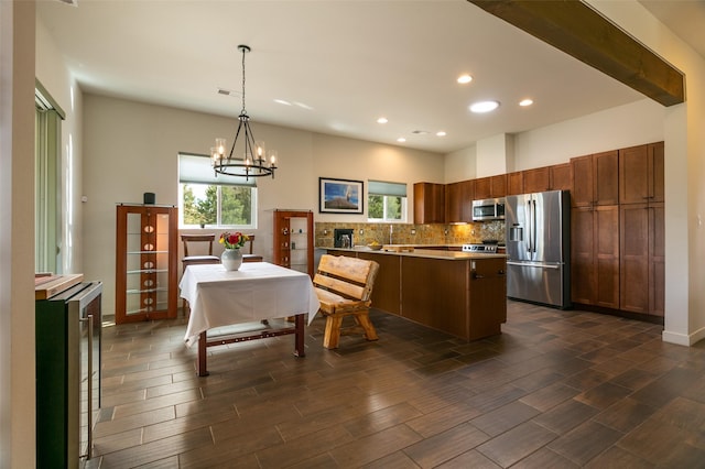 kitchen with wood tiled floor, appliances with stainless steel finishes, pendant lighting, a notable chandelier, and backsplash