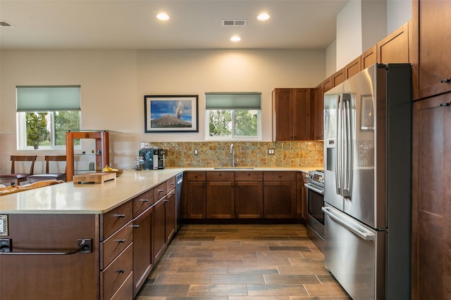 kitchen featuring visible vents, light countertops, a peninsula, stainless steel appliances, and a sink