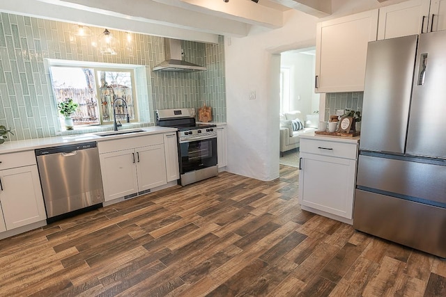 kitchen with a sink, tasteful backsplash, stainless steel appliances, wall chimney exhaust hood, and dark wood-style flooring