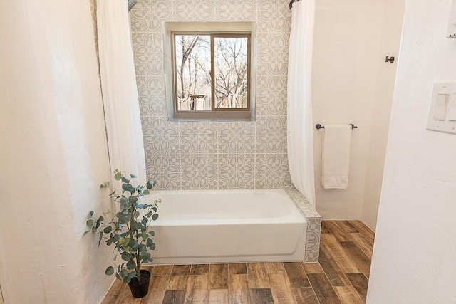 bathroom featuring wood finished floors and bathtub / shower combination