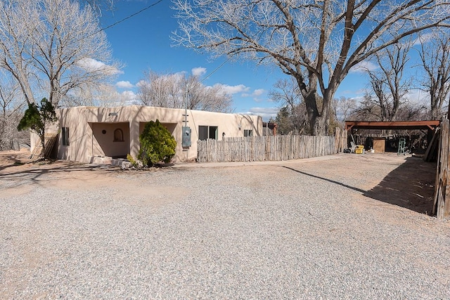 pueblo-style house with a carport and fence