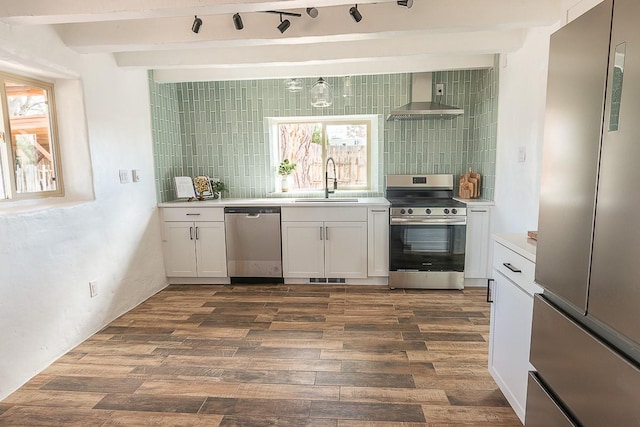 kitchen featuring tasteful backsplash, a sink, stainless steel appliances, wall chimney exhaust hood, and dark wood-style flooring