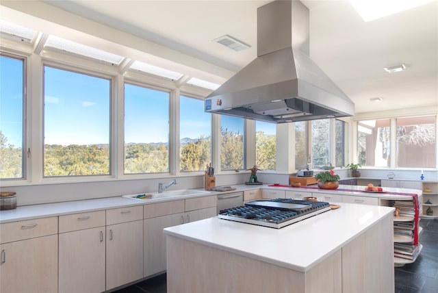 kitchen featuring light countertops, plenty of natural light, island exhaust hood, and a sink