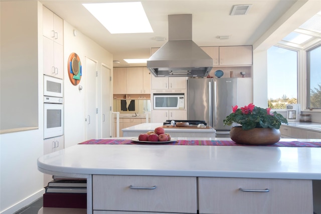 kitchen with visible vents, light countertops, a skylight, island range hood, and white appliances