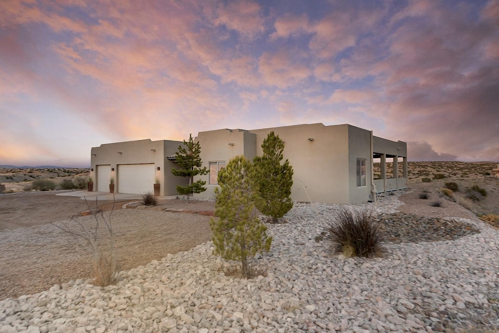 view of side of property with concrete driveway, an attached garage, and stucco siding