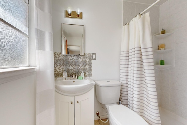 full bath featuring tasteful backsplash, toilet, a tile shower, and vanity