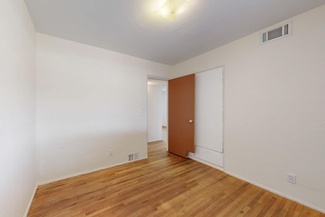 unfurnished room with visible vents, light wood-type flooring, and baseboards