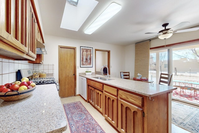 kitchen with a peninsula, under cabinet range hood, decorative backsplash, stainless steel gas stove, and a sink