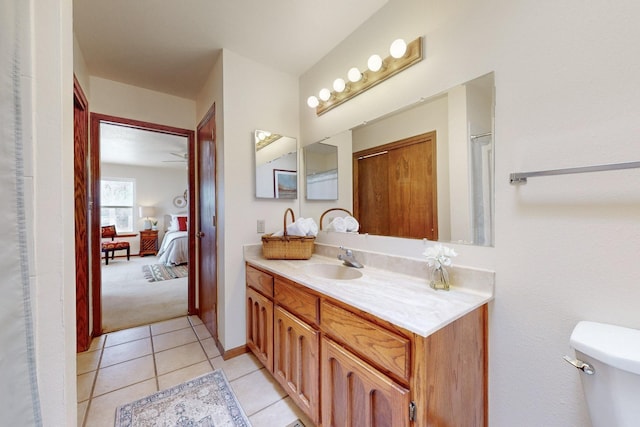 ensuite bathroom featuring tile patterned flooring, toilet, connected bathroom, and vanity