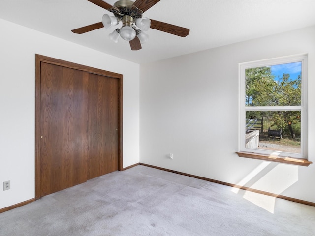 unfurnished bedroom with light carpet, a closet, baseboards, and a ceiling fan