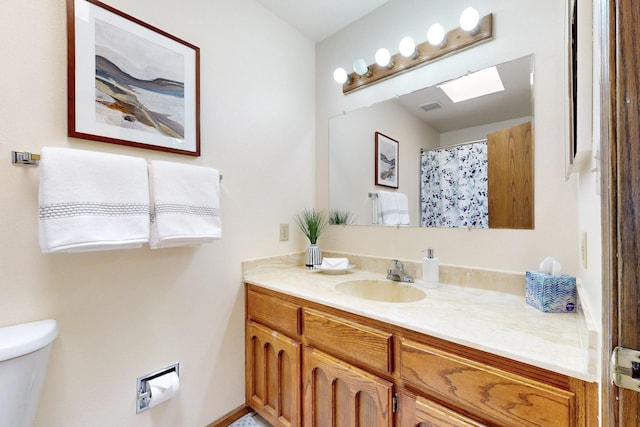 full bathroom featuring visible vents, curtained shower, toilet, vanity, and a skylight