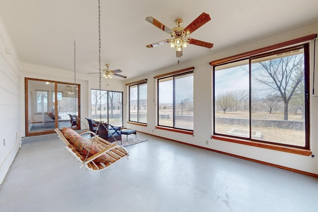 sunroom featuring baseboards and finished concrete flooring