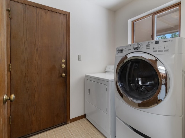 washroom with baseboards, separate washer and dryer, and laundry area