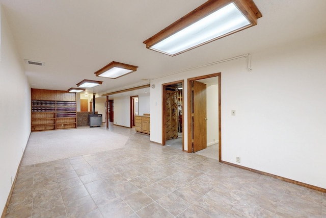 unfurnished living room with a wood stove, visible vents, and baseboards