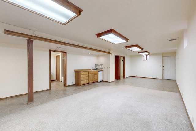 finished basement with visible vents, baseboards, and light carpet