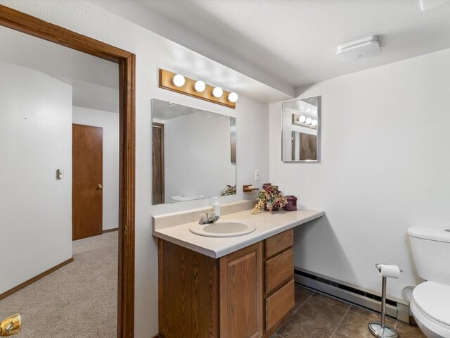 bathroom with vanity, a baseboard heating unit, baseboards, and toilet