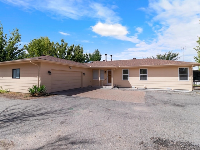 ranch-style house with aphalt driveway and an attached garage