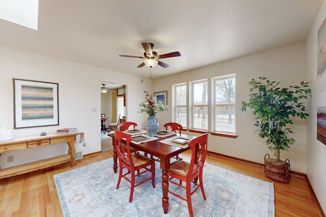 dining space with wood finished floors, ceiling fan, and baseboards