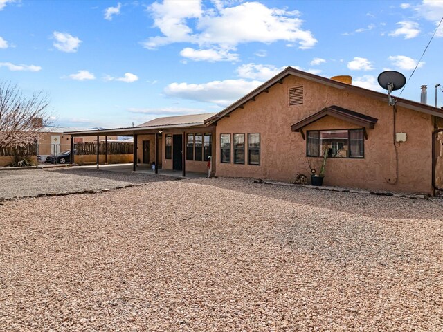 902 Calle Loma, Espanola, NM 87532 - back of property with fence, stucco siding, a carport, a patio area, and metal roof