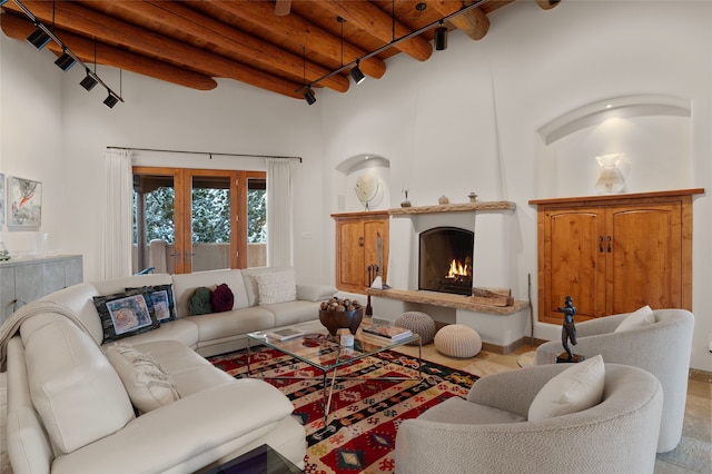 living room featuring beamed ceiling, wood ceiling, a towering ceiling, and a large fireplace