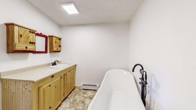 bathroom with baseboards, vanity, baseboard heating, a freestanding tub, and a textured ceiling