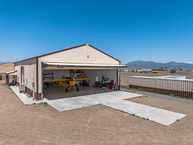 back of house with a mountain view, an outdoor structure, and cooling unit