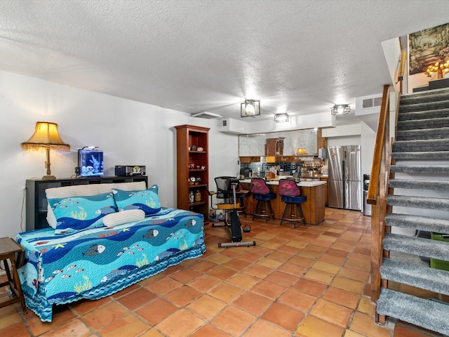 bedroom featuring visible vents, a textured ceiling, and freestanding refrigerator
