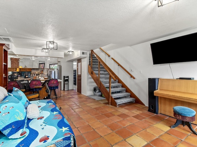living area featuring light tile patterned floors, visible vents, a textured ceiling, and stairs