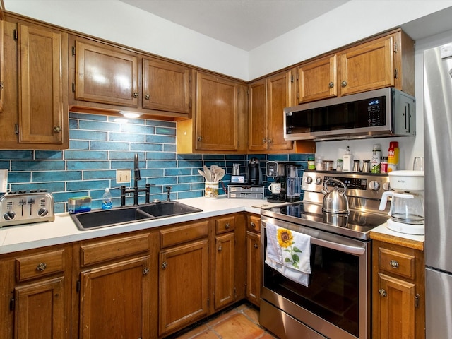 kitchen featuring a sink, light countertops, brown cabinetry, and stainless steel appliances