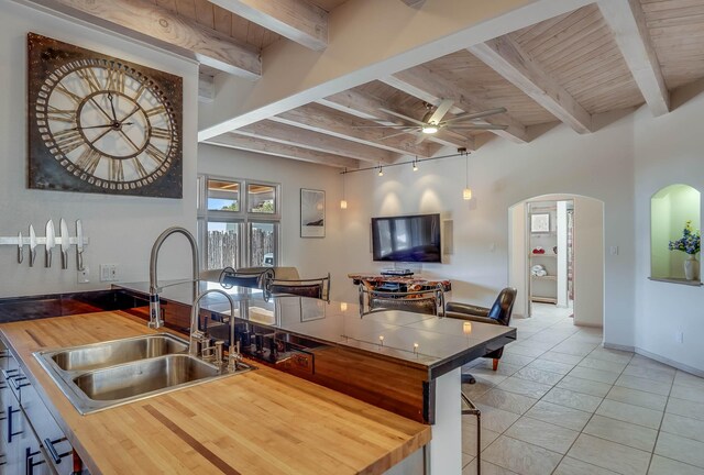 778 Camino Francisca, Santa Fe, NM 87506 - kitchen featuring a sink, butcher block counters, arched walkways, beamed ceiling, and a ceiling fan