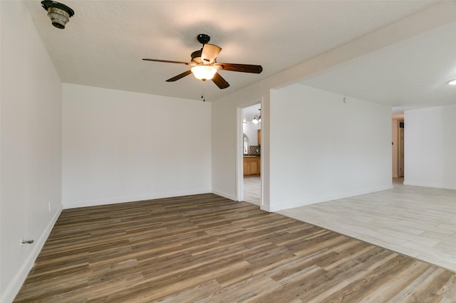 empty room featuring a ceiling fan, wood finished floors, and baseboards
