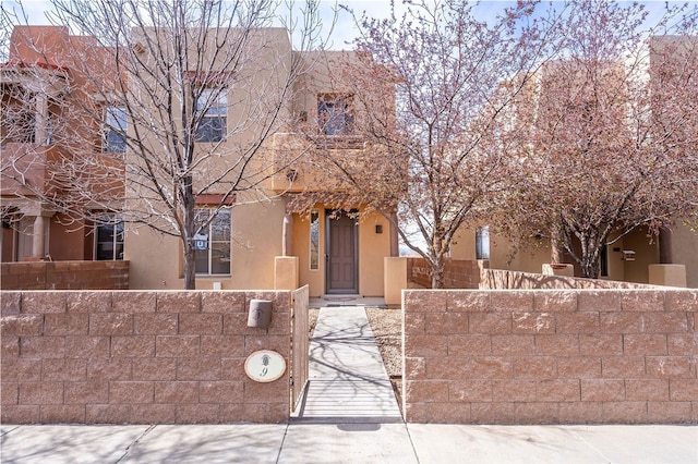 9 E Saddleback Mesa, Santa Fe, NM 87508 - pueblo-style house featuring a fenced front yard and stucco siding