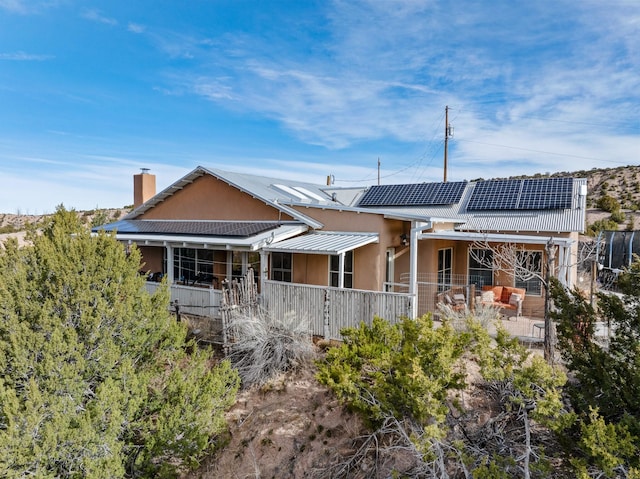75A Camino Chupadero, Santa Fe, NM 87506 - back of house featuring solar panels, a chimney, a patio, and stucco siding