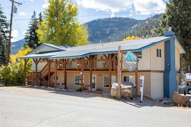 rear view of house with metal roof, a standing seam roof, and a mountain view