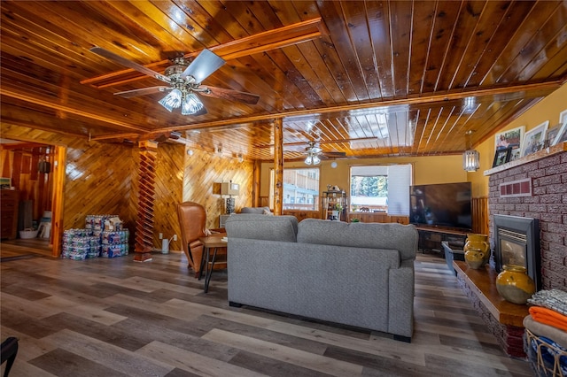 living room featuring visible vents, ceiling fan, wood finished floors, a glass covered fireplace, and wooden ceiling
