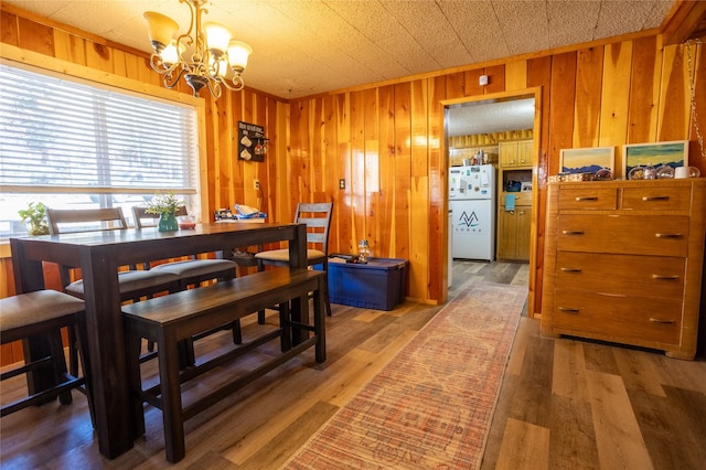 dining room with wooden walls, a chandelier, and light wood-type flooring
