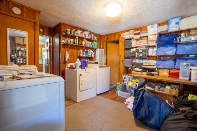 clothes washing area with independent washer and dryer, wood walls, laundry area, and a textured ceiling