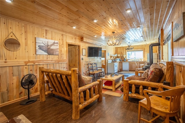 living room with a notable chandelier, wooden walls, wood ceiling, and dark wood-style flooring