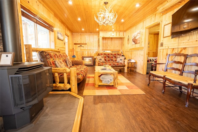 living room with an inviting chandelier, wood finished floors, wooden ceiling, and a wood stove