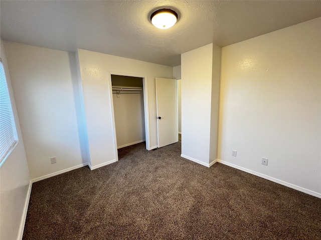 1666 Calle De Oriente Norte, Santa Fe, NM 87507 - unfurnished bedroom featuring baseboards, a textured ceiling, a closet, and dark colored carpet