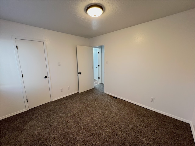1666 Calle De Oriente Norte, Santa Fe, NM 87507 - unfurnished bedroom with baseboards, visible vents, dark carpet, and a textured ceiling