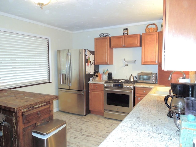 kitchen with crown molding, a sink, brown cabinets, and appliances with stainless steel finishes