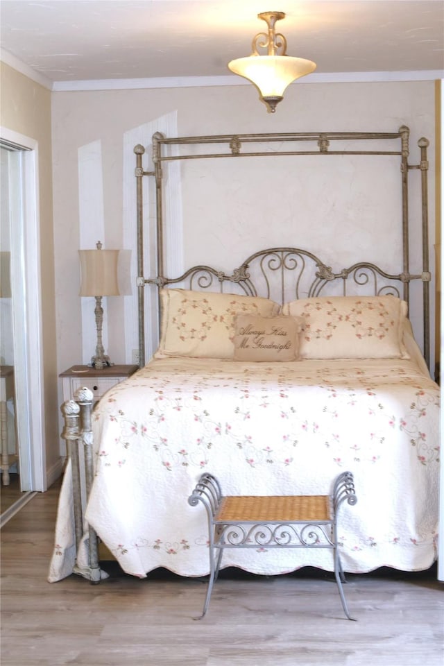 bedroom with crown molding and wood finished floors