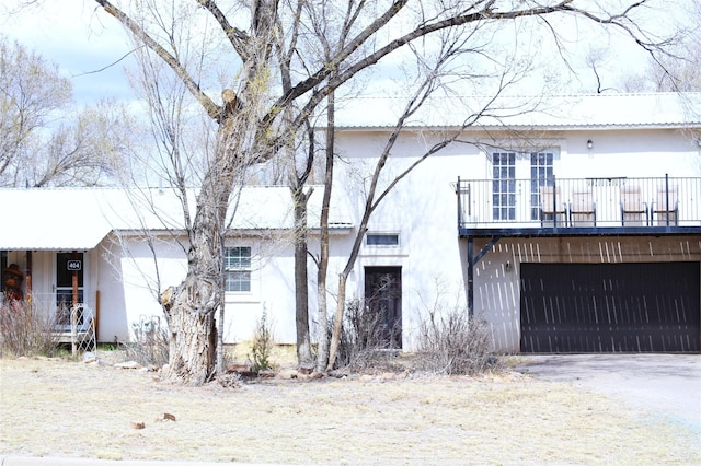view of front of house featuring a balcony, driveway, stucco siding, and an attached garage