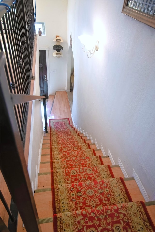 stairway featuring baseboards and arched walkways