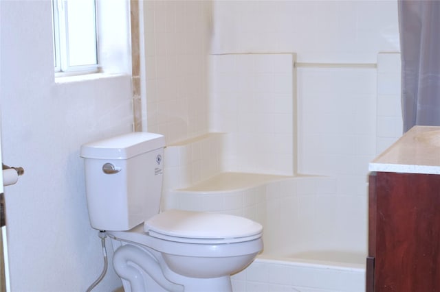bathroom with toilet, tiled shower, and vanity