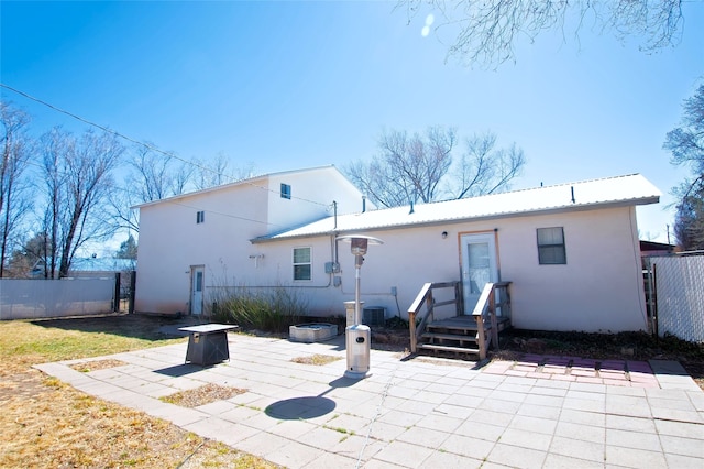 back of house with a fire pit, a patio area, stucco siding, fence, and metal roof