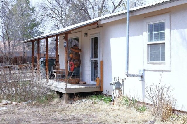 view of side of property featuring stucco siding, fence, and metal roof