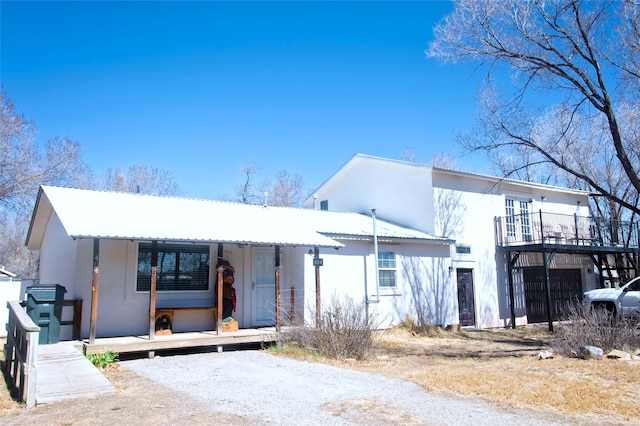 view of front of house featuring a balcony, stucco siding, and metal roof